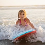 young girl boogie boarding in ocean | Sunset Vacations