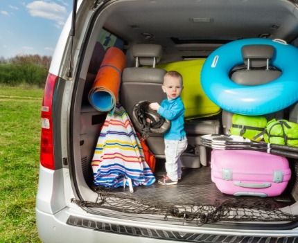 Kid in minivan packed for the beach | Sunset Vacations